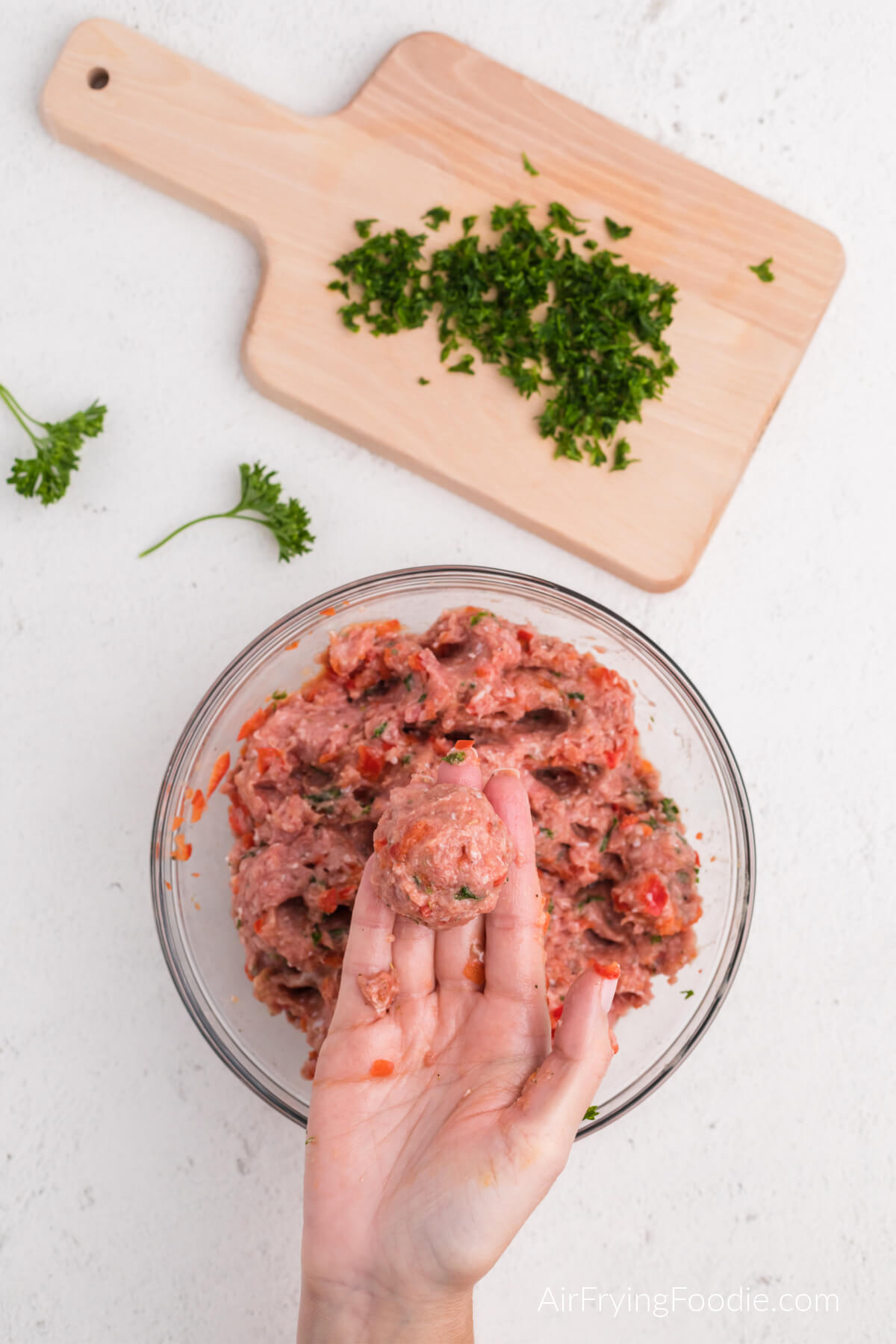 Hand holding a scooped and shaped meatball with the turkey and ingredients. 