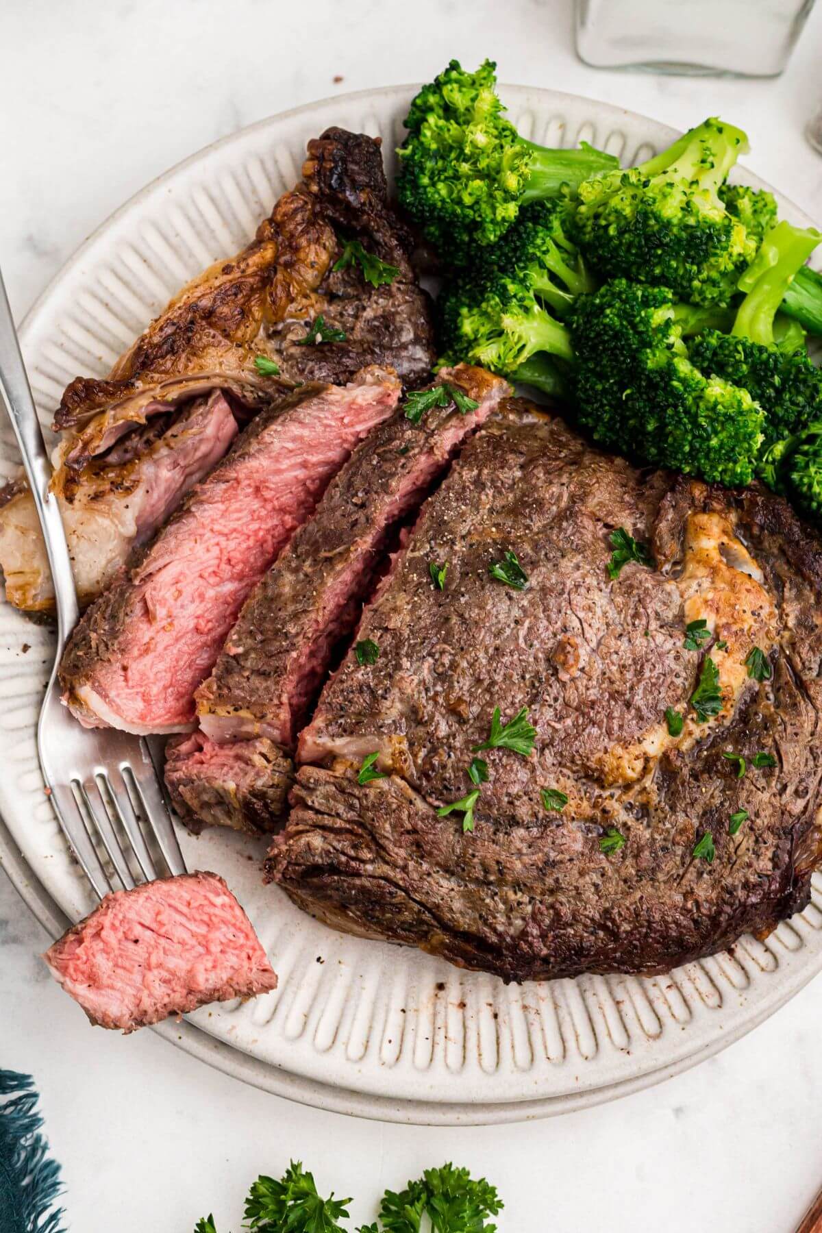 Juicy steak sliced and served with broccoli on a white plate. 