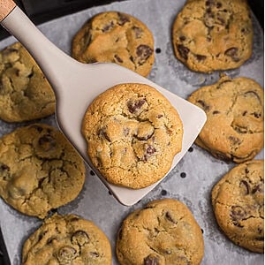 Chocolate chip cookies on parchment paper in air fryer basket.
