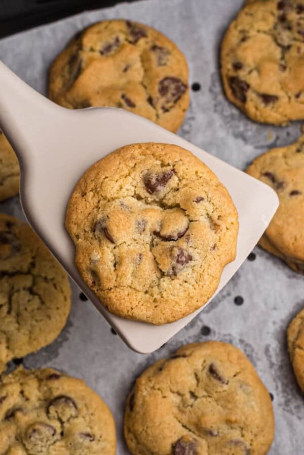 Chocolate chip cookies on parchment paper in air fryer basket.