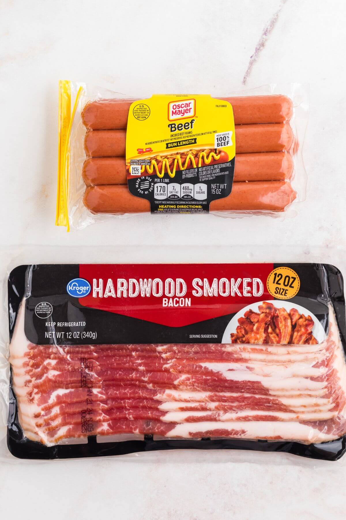 Hot dogs and a pack of bacon on a marble table. 