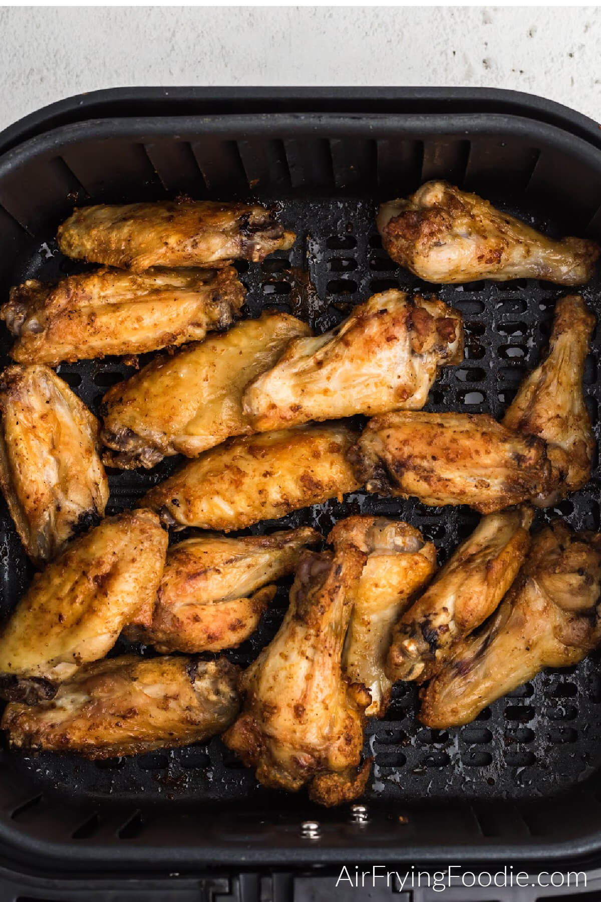 Chicken wings in air fryer basket, cooked and ready to be tossed in sauce. 