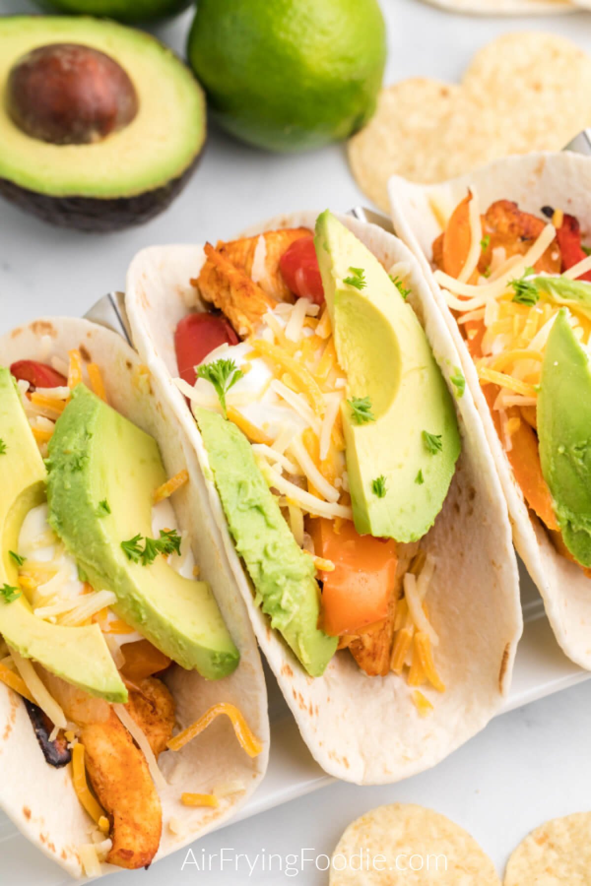 chicken fajitas topped with avocado and cheese, ready to serve. 
