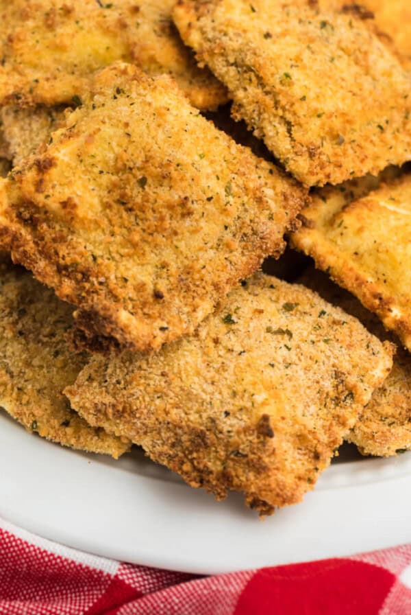 Close up of fried ravioli on a white plate ready to serve.