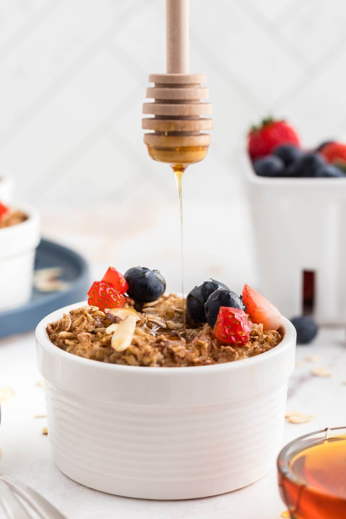Golden oatmeal topped with fruit and being drizzled with honey. 