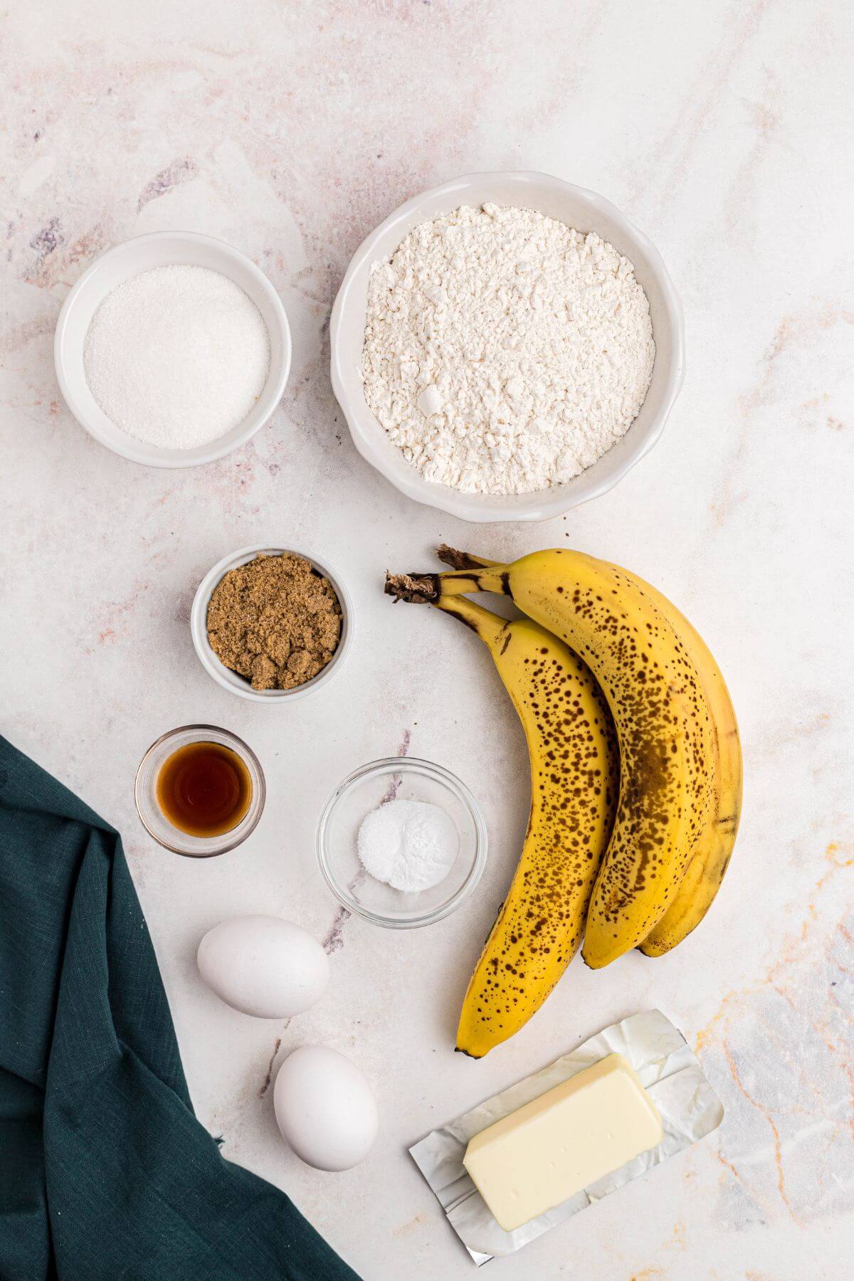 Ingredients for banana bread measured out on a marble table. 