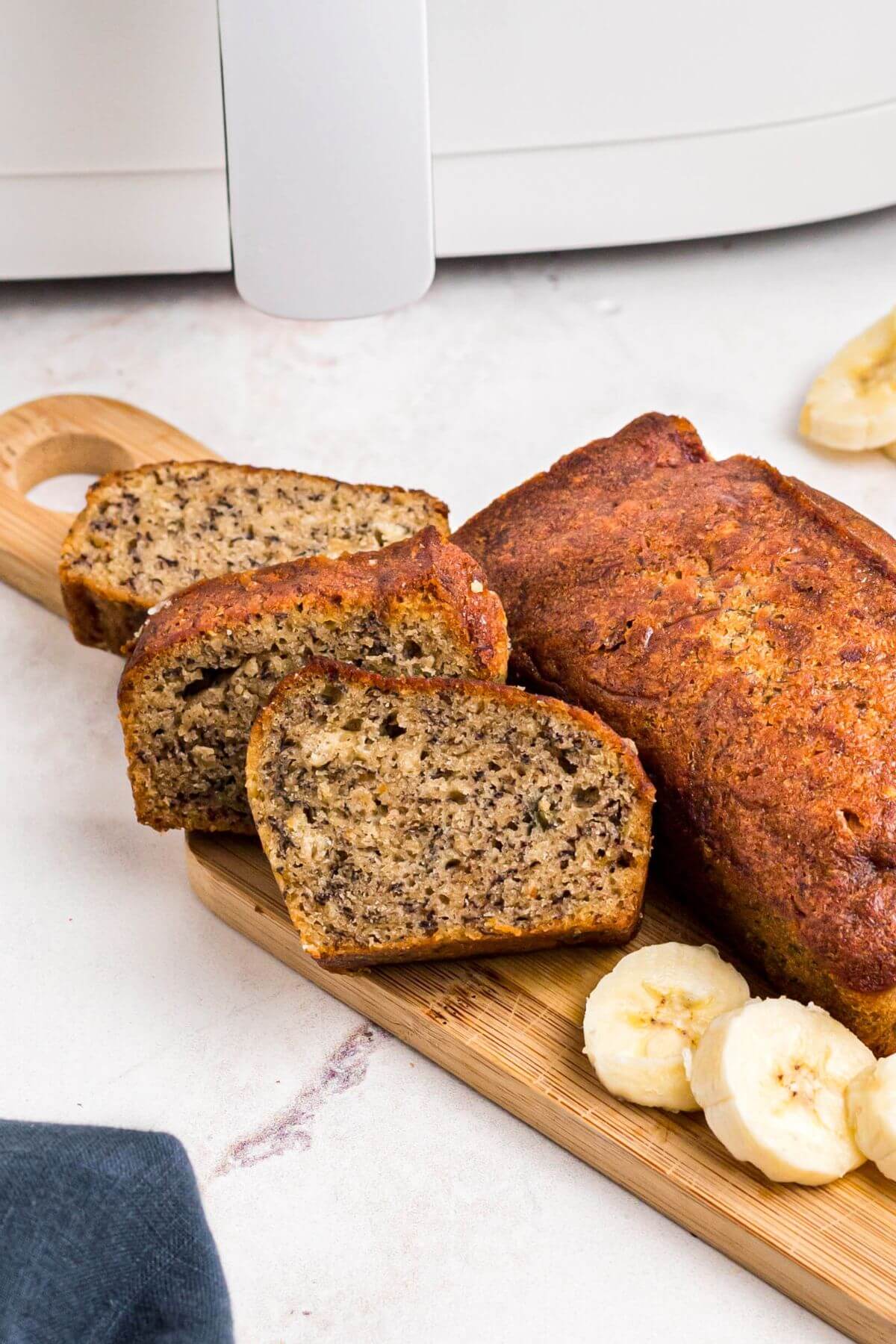 Golden baked banana bread on a wooden cutting board with banana slices. 