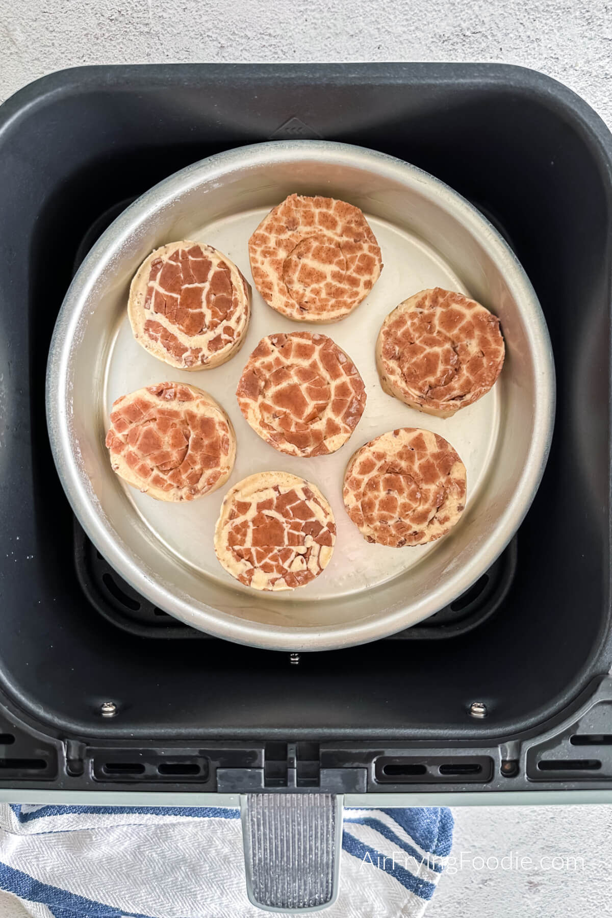 Cinnamon rolls in air fryer in a pan, ready to be air fried. 