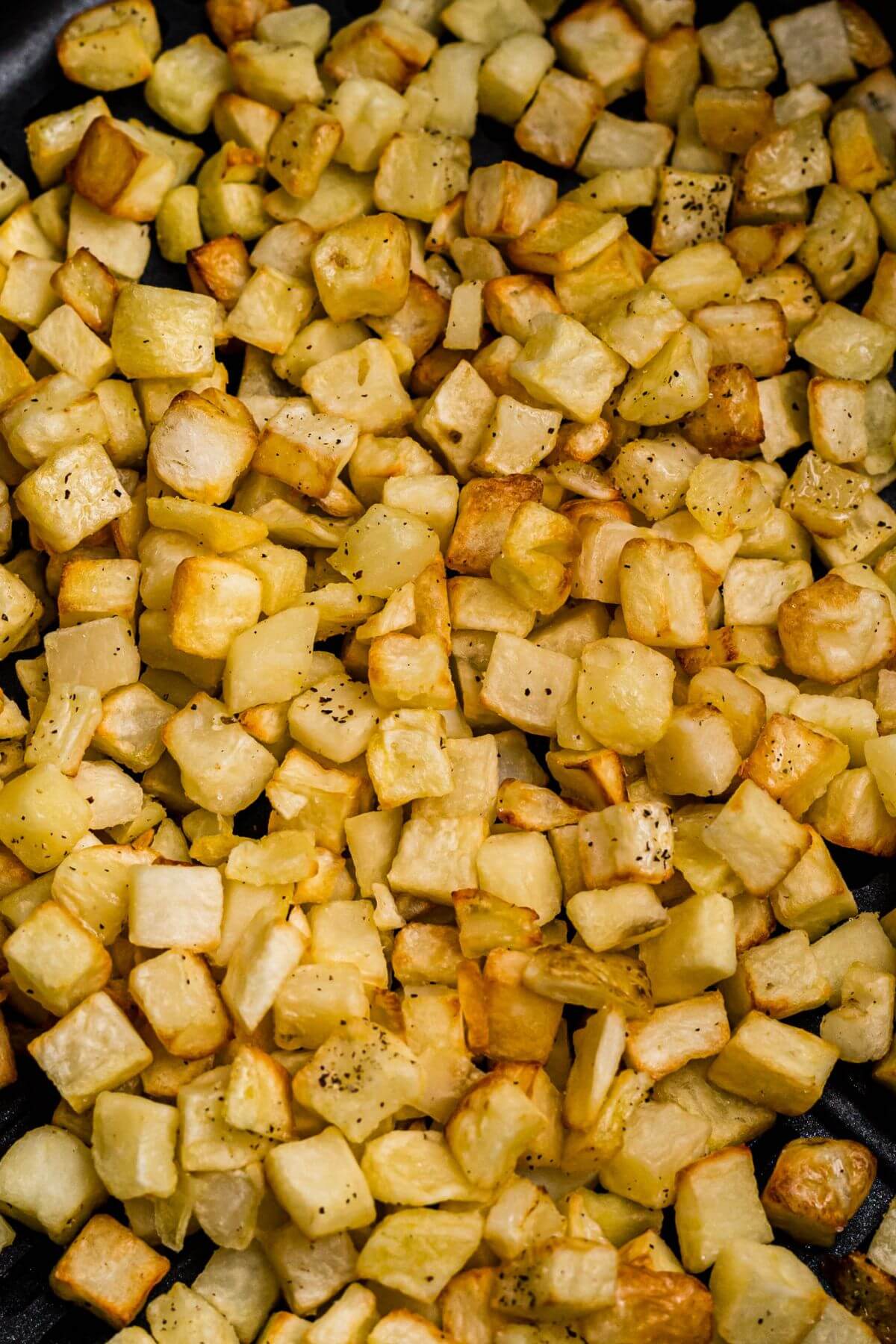 Golden and crispy cooked diced potatoes after being cooked and seasoned in the air fryer. 