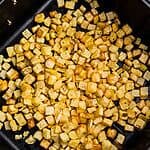 Golden and crispy cooked diced potatoes after being cooked and seasoned in the air fryer.