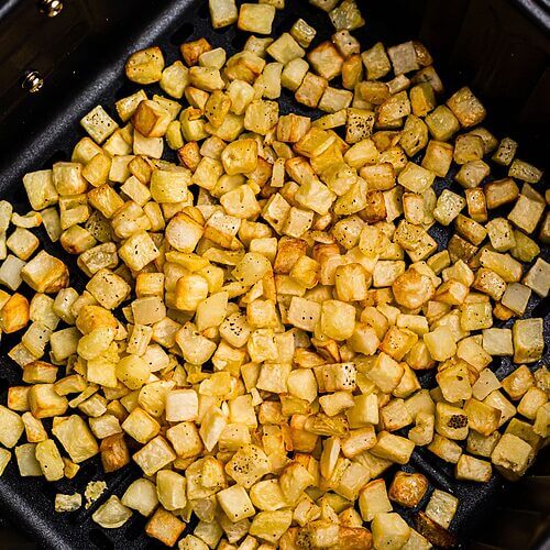 Golden and crispy cooked diced potatoes after being cooked and seasoned in the air fryer.