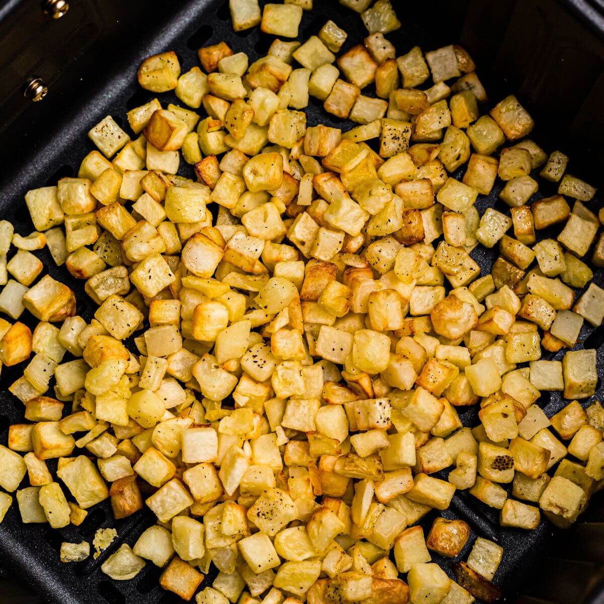 Golden and crispy cooked diced potatoes after being cooked and seasoned in the air fryer.