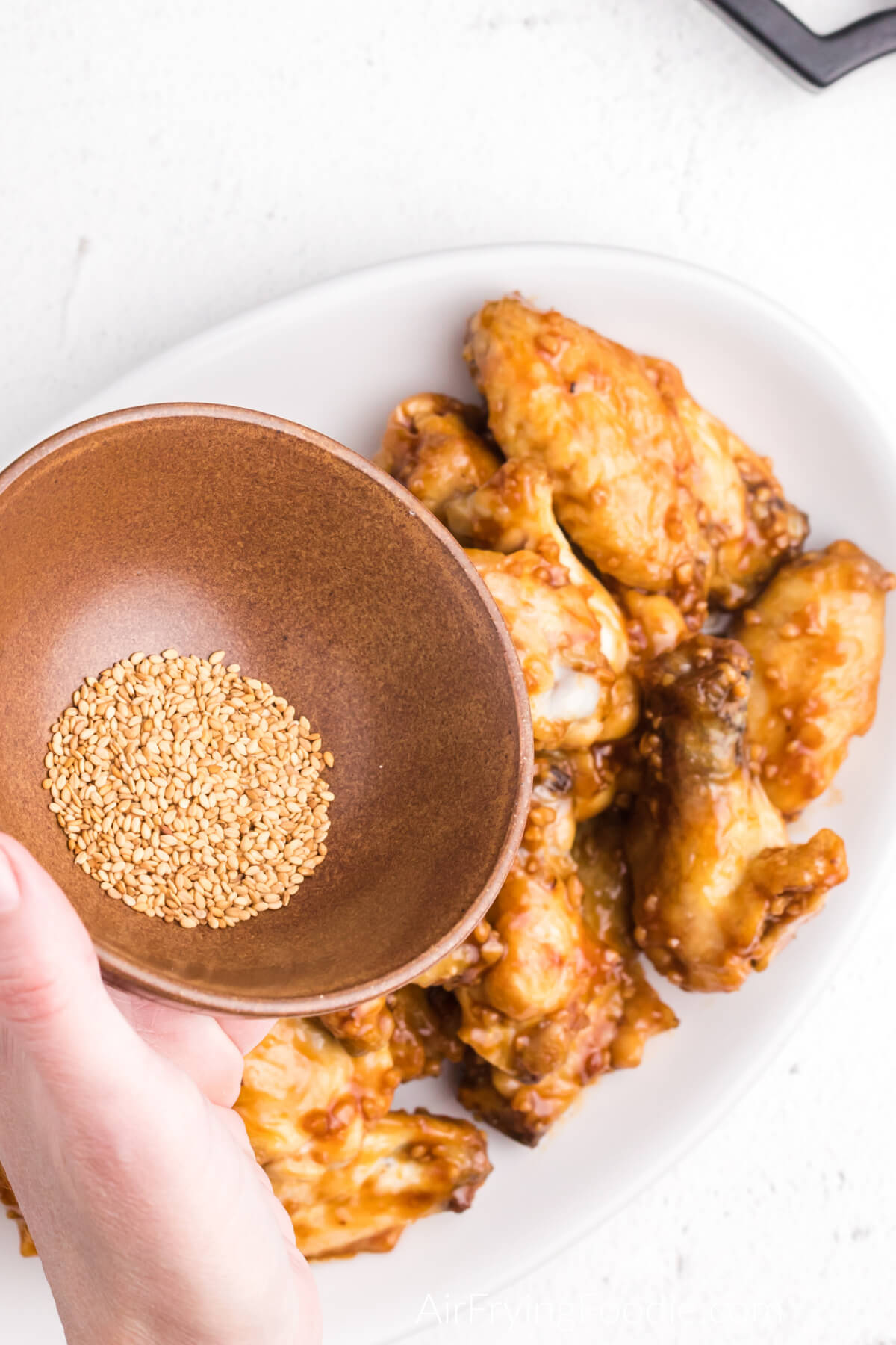 Sesame seeds about to be sprinkled over the honey garlic chicken wings. 