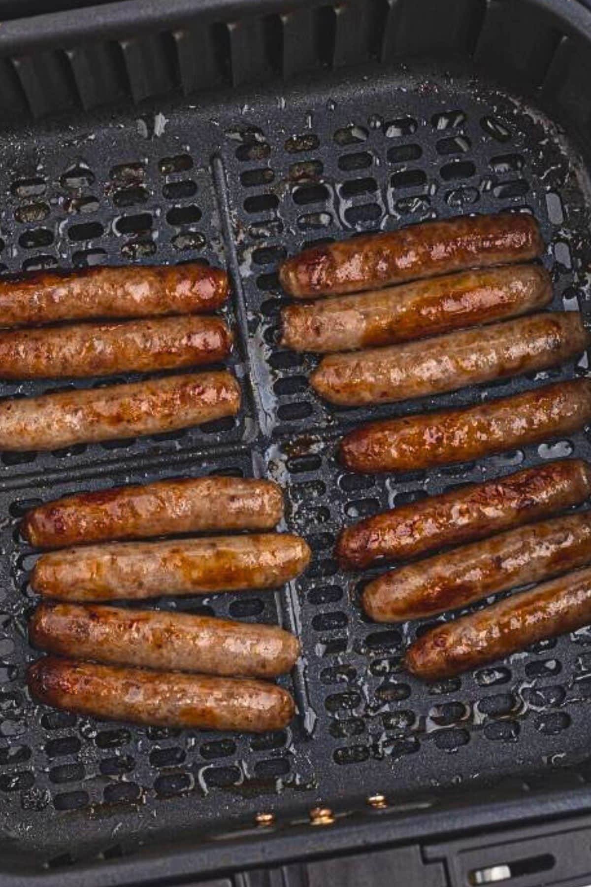 Golden brown, cooked sausage links in the air fryer basket after being cooked. 