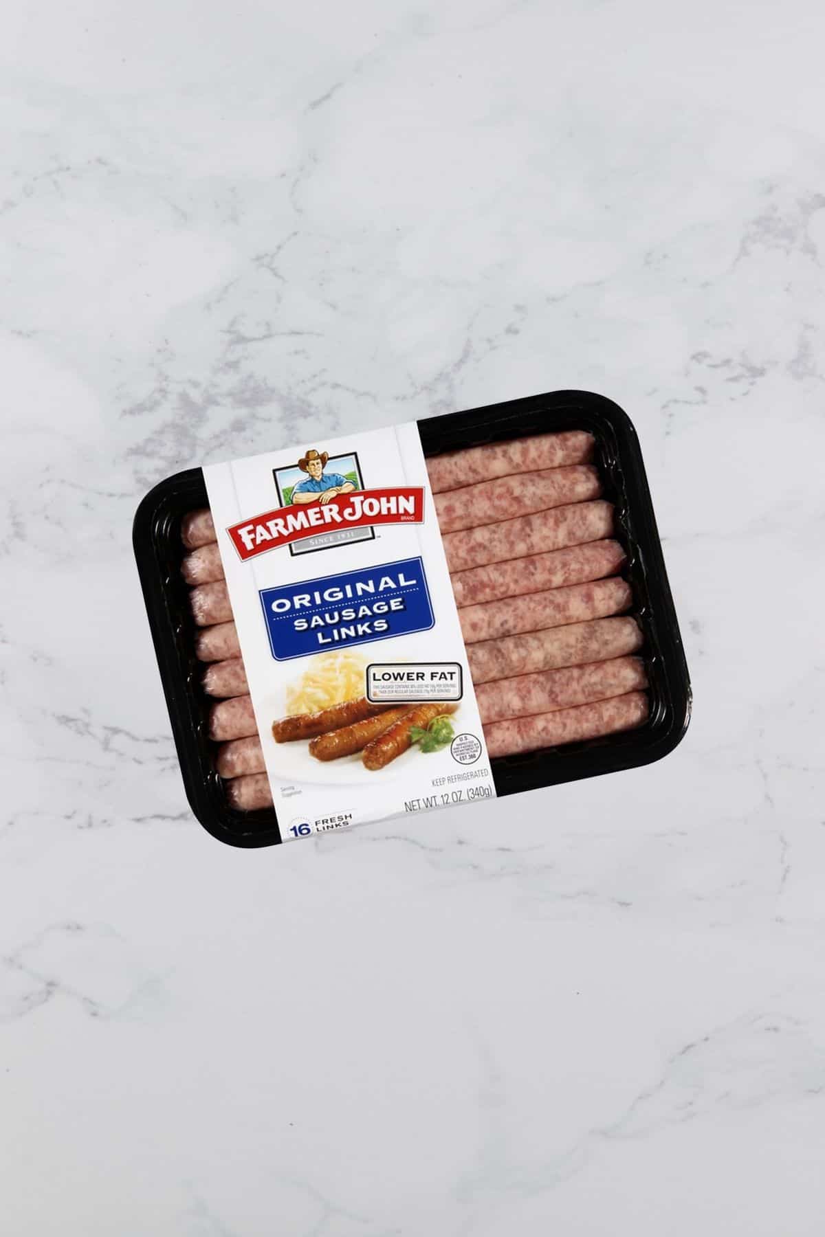 Package of sausage links on a marble table. 
