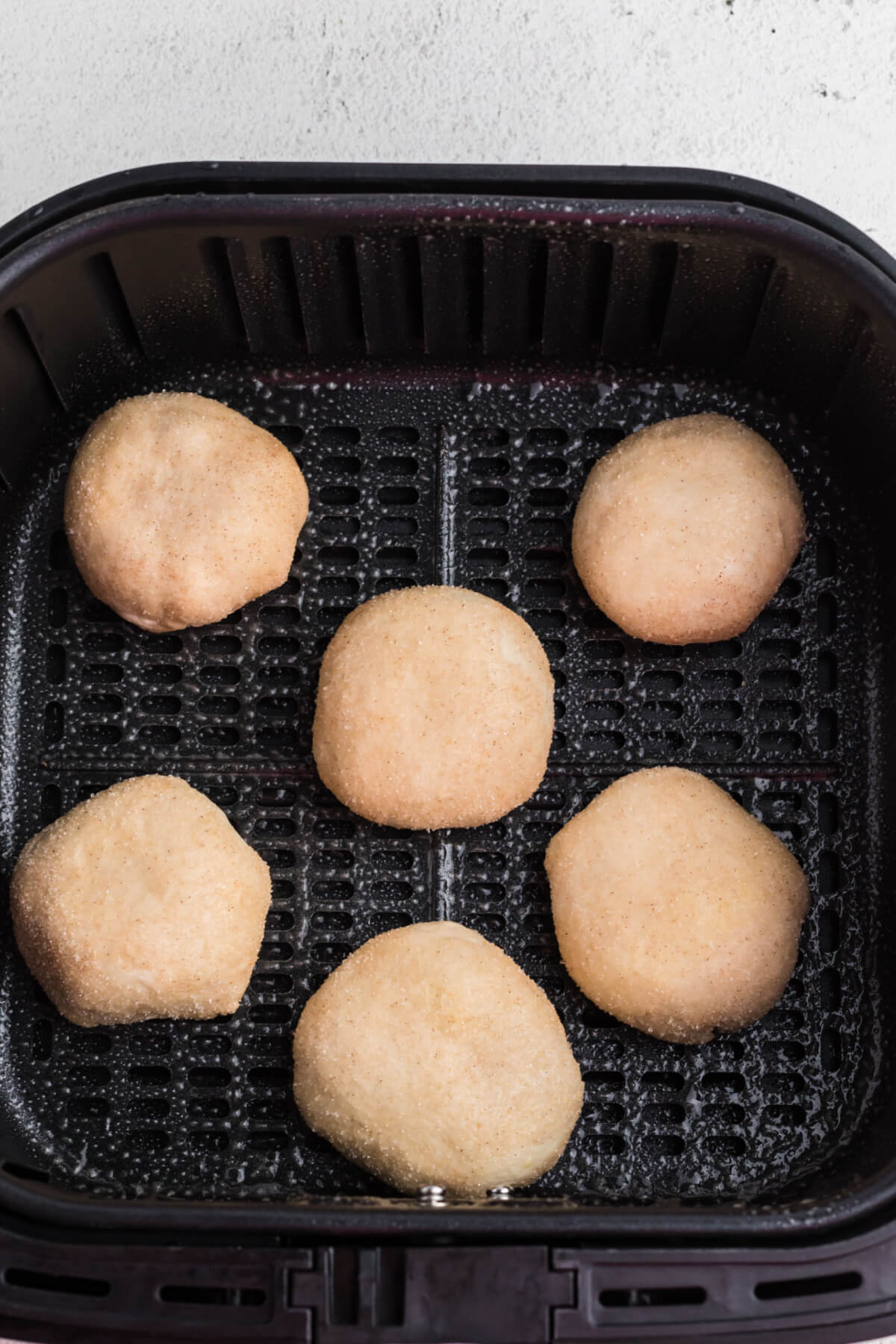 biscuit dough placed into the basket of the air fryer and the tops have been sprayed with oil. ready to cook. 