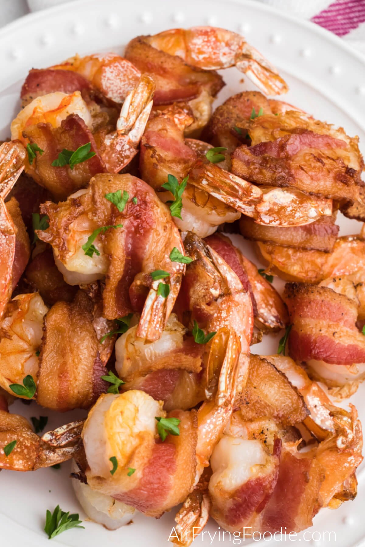 close up of air fryer bacon wrapped shrimp served on a white plate and ready to eat. 