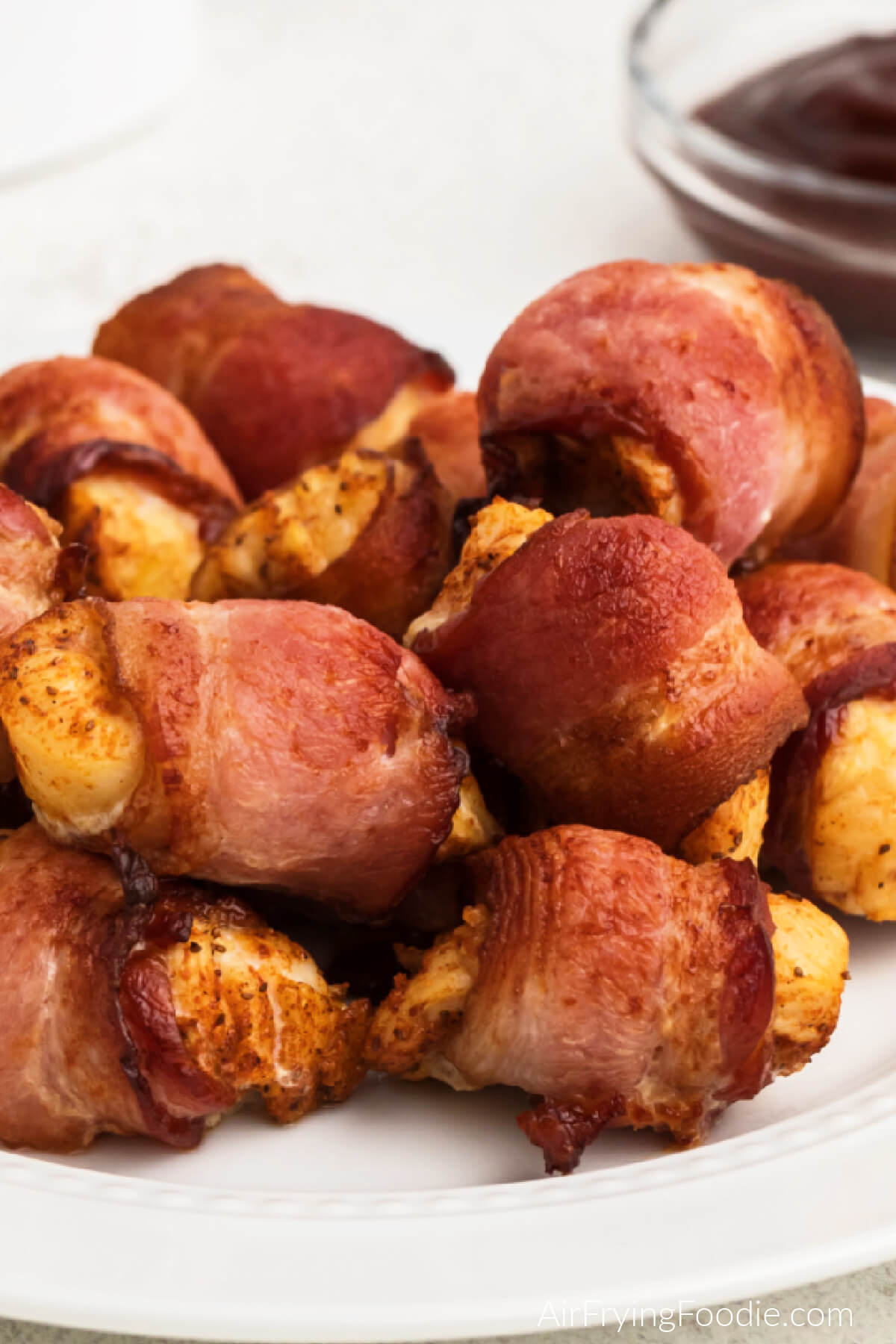 Bacon wrapped chicken bites made in the air fryer and served on a white plate. 