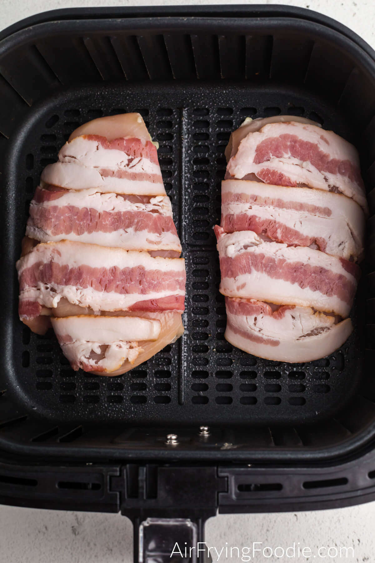 Chicken wrapped in bacon and place into the basket of the air fryer. 