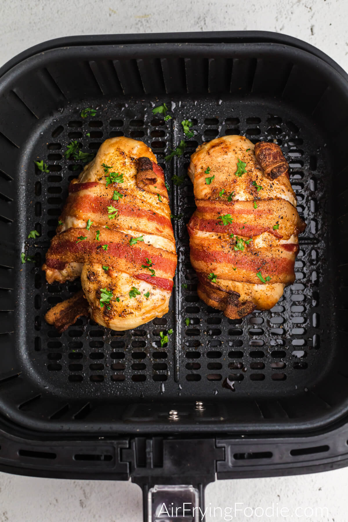 Air fried bacon wrapped chicken in the basket of the air fryer.
