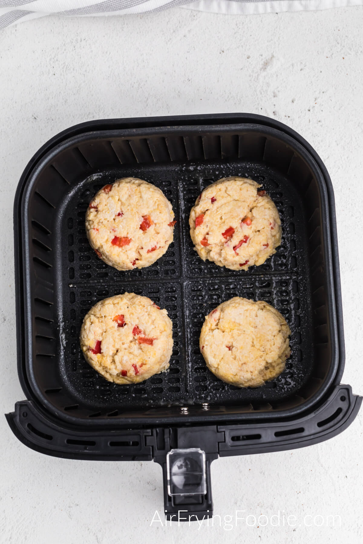 Crab cakes in the basket of the air fryer, ready to air fry. 