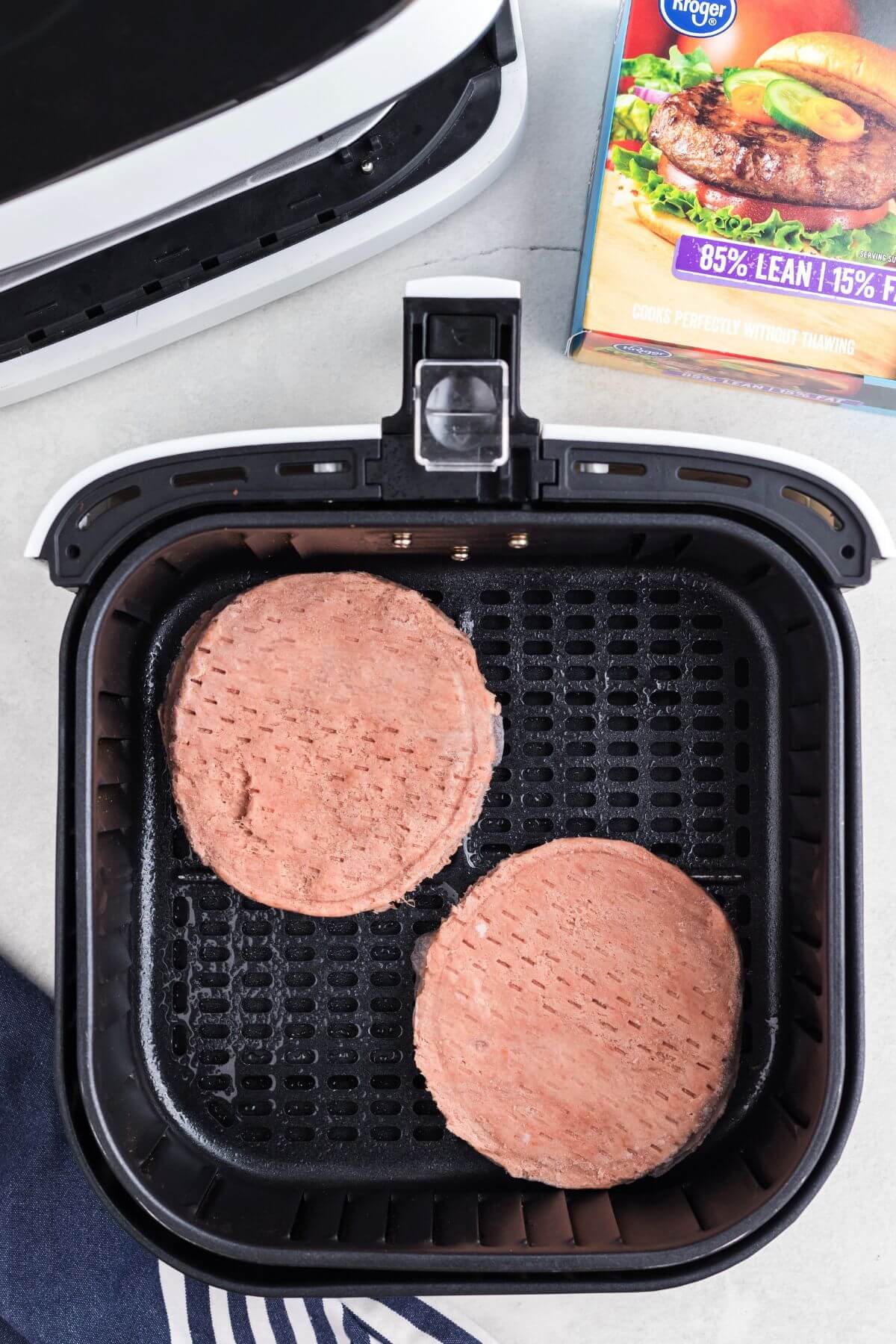 Frozen turkey burger patties in the air fryer basket before being cooked. 