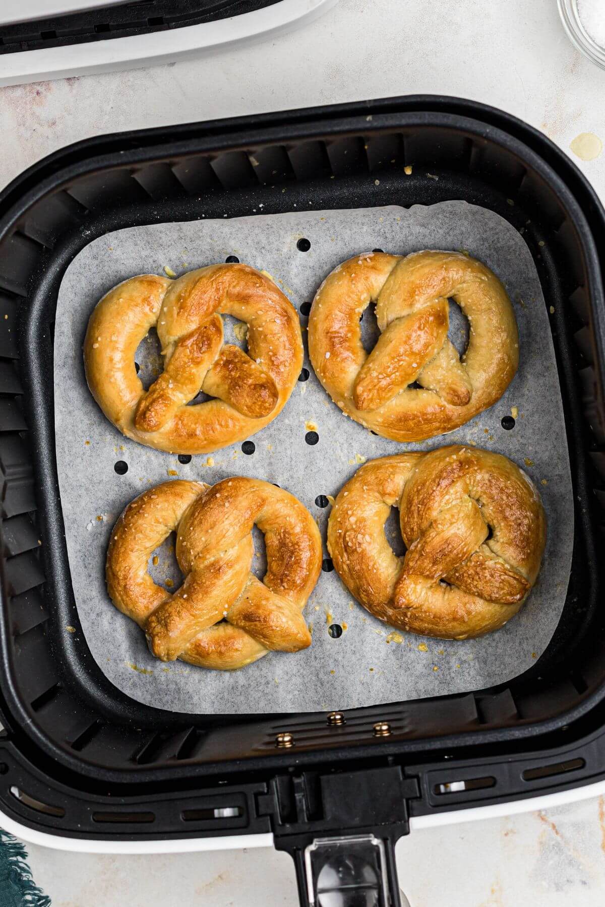 Golden brown soft pretzels in the air fryer basket after being cooked. 