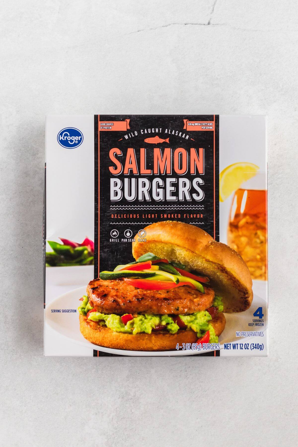 Box of frozen salmon burgers on a white marble table. 