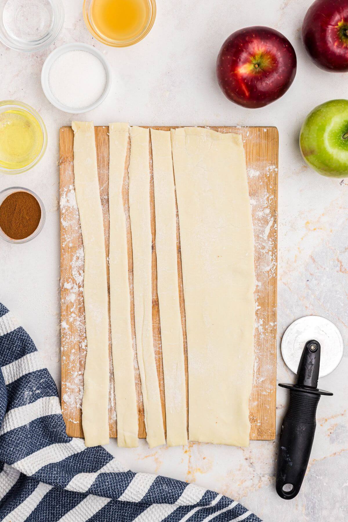 Puff pastry sheet rolled out and cut into slices on a wooden cutting board. 