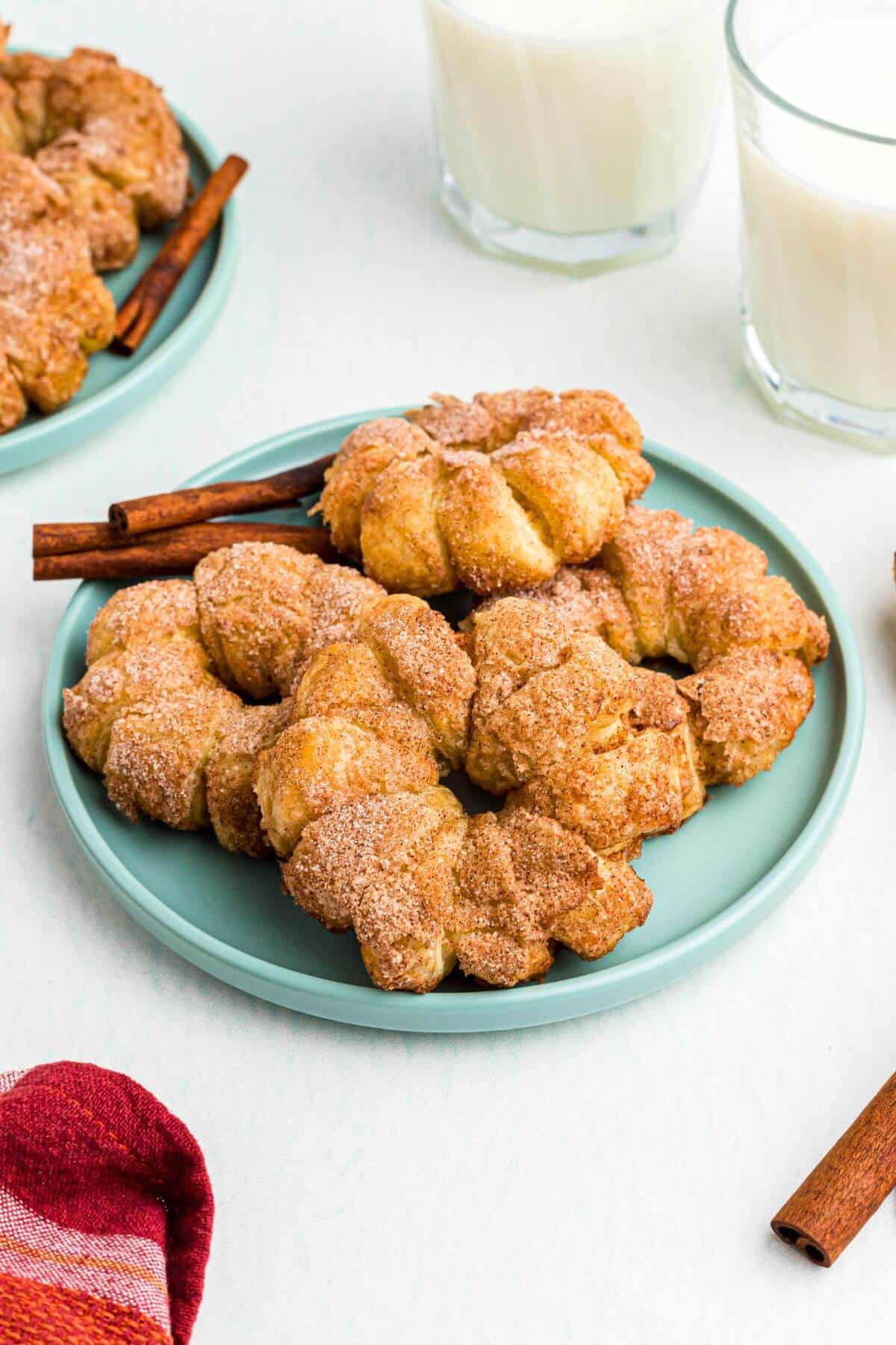 Golden puff pastry wrapped apple rings that have been air fried and are on a light green plate. 