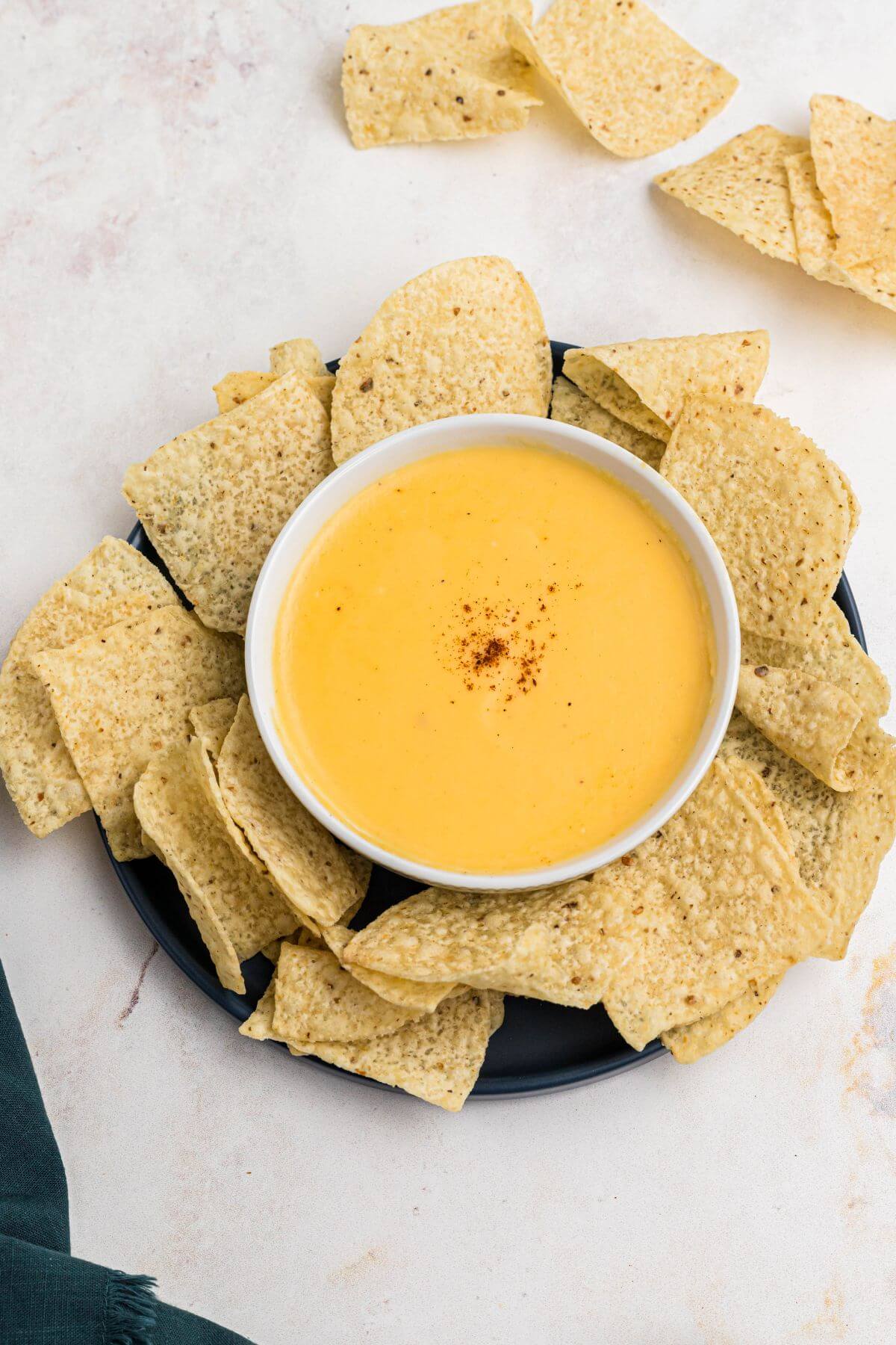 Creamy cheese sauce in a white bowl surrounded by tortilla chips. 