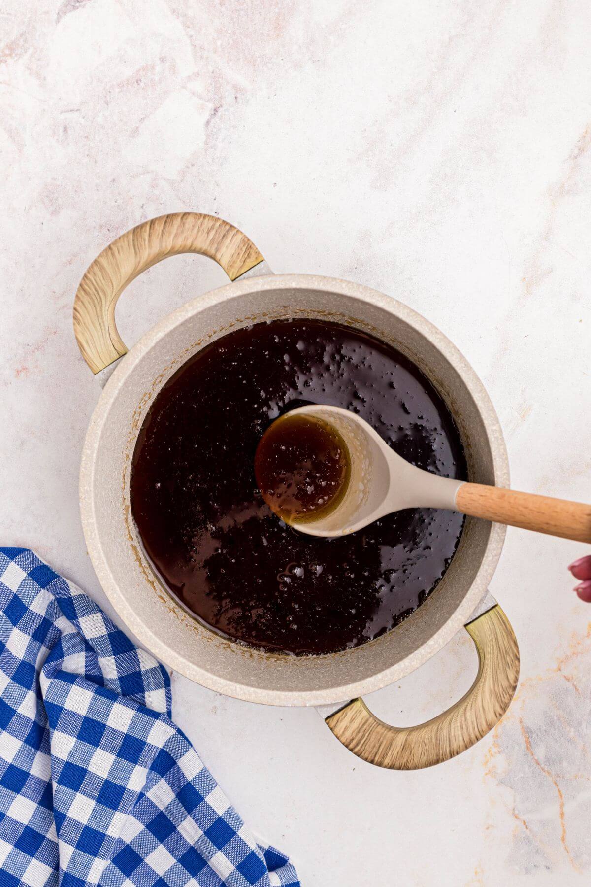 Sugars dissolved into water with maple extract in a medium saucepan making homemade syrup. 