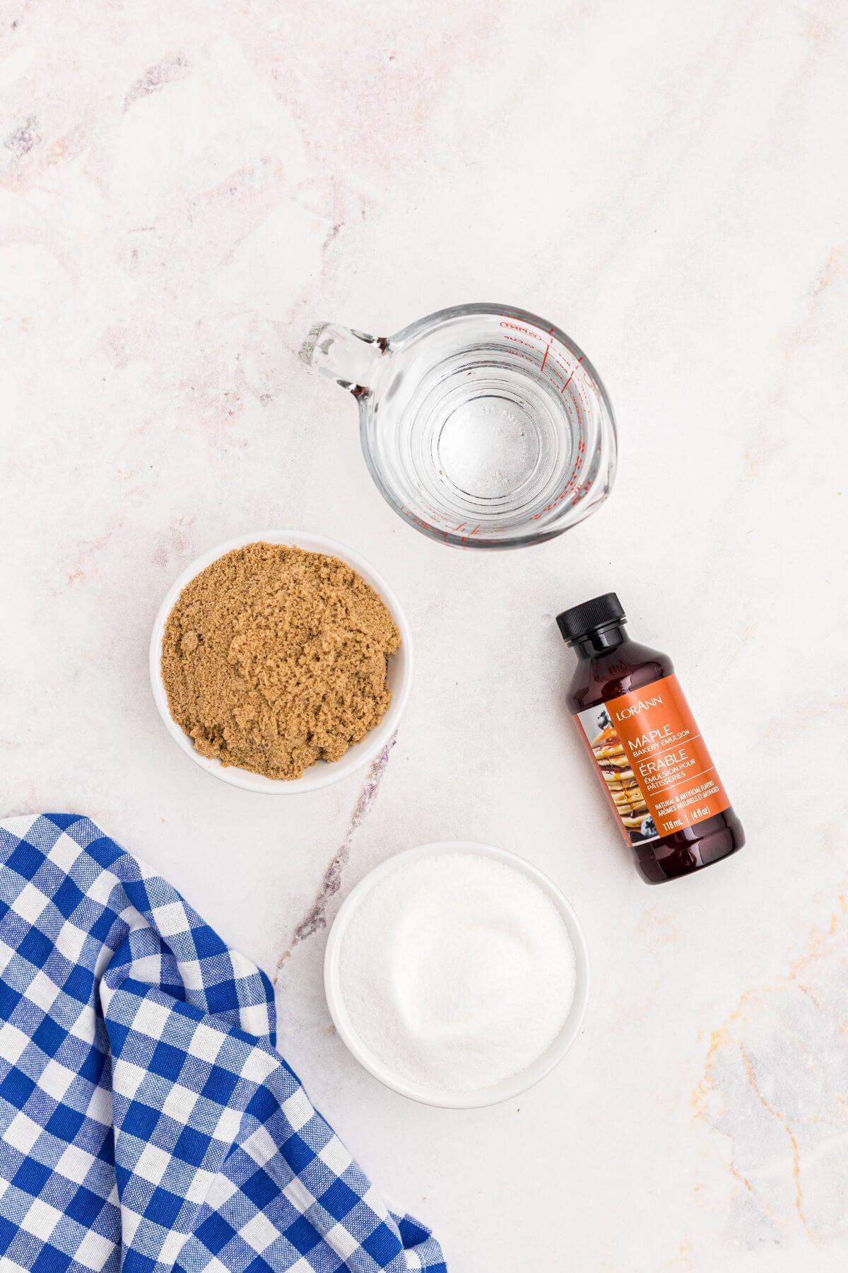 Sugar, brown sugar, water, and maple extract on a marble table. 