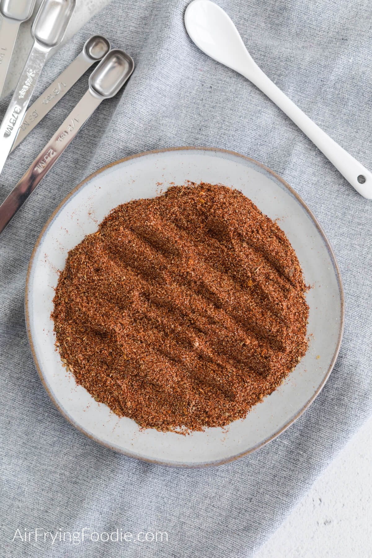 Overhead photo of homemade taco seasoning on a plate with measuring spoons and a serving spoon. 