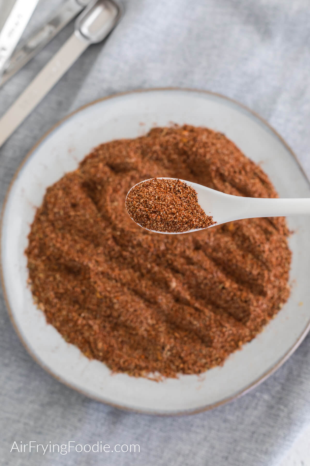 Taco seasoning on a plate with a spoon full of the taco seasoning closer to the camera. 