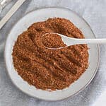 Overhead photo of homemade taco seasoning on a white plate with a spoonful of the seasoning close up.