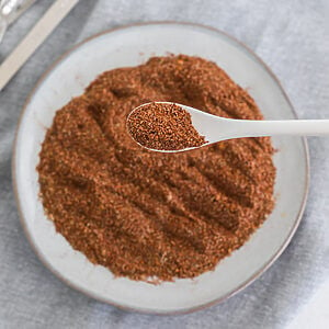 Overhead photo of homemade taco seasoning on a white plate with a spoonful of the seasoning close up.