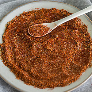 Homemade BBQ rub recipe to use on meats and vegetables, on a white plate.
