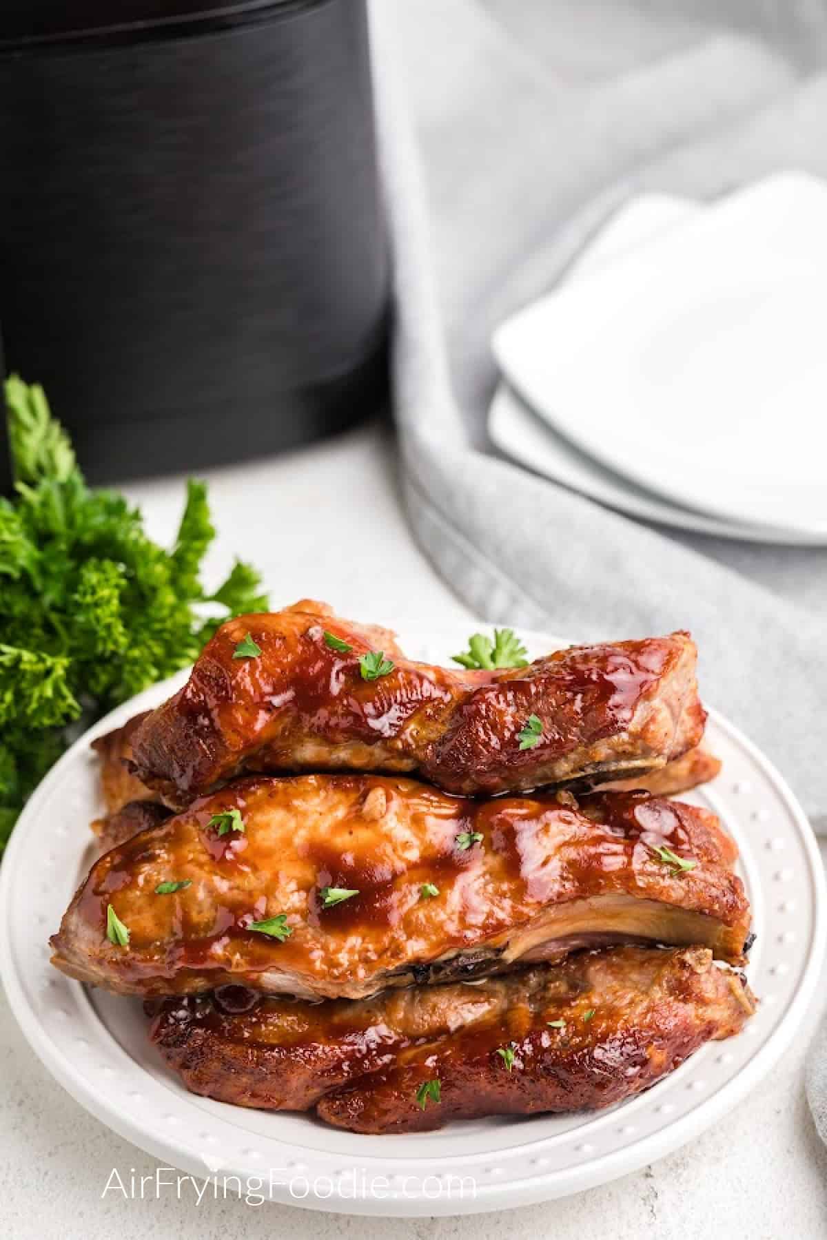 Air Fried Country Style Ribs on a white plate and with parsley sprinkled on top before serving. 