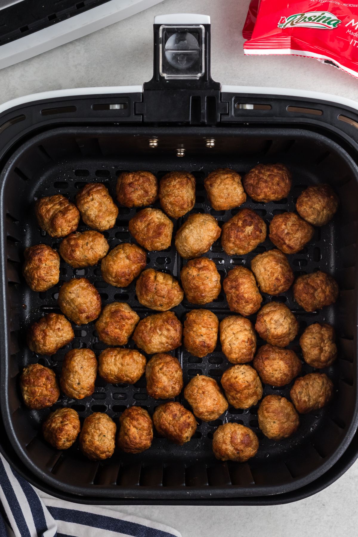 Golden brown meatballs in the air fryer basket after being cooked. 