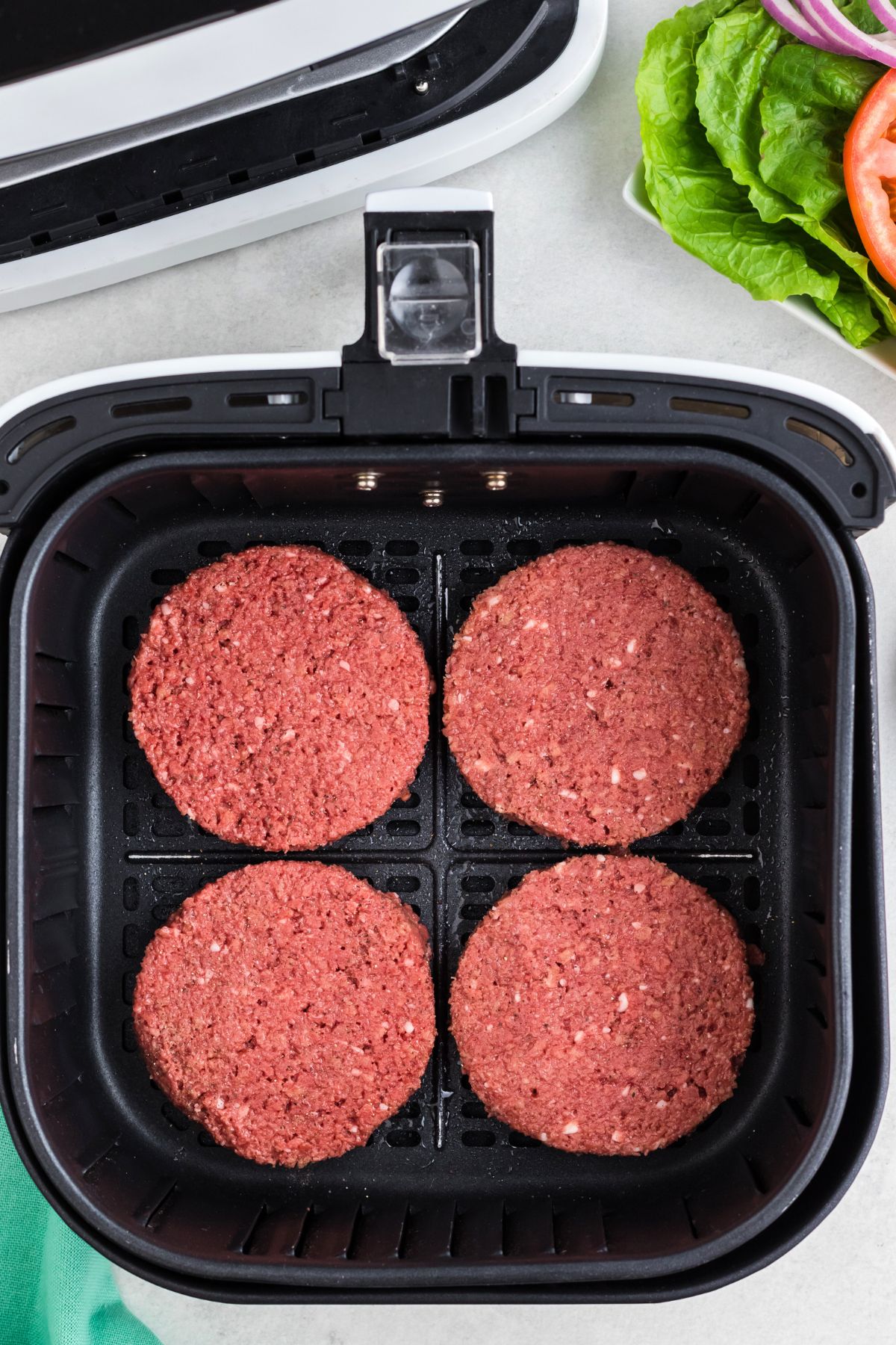 Uncooked impossible burger patties in the air fryer basket. 