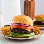 Impossible burger in a bun with traditional burger toppings on a small plate with fries.