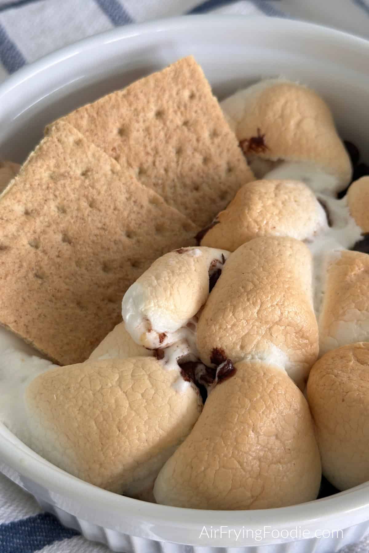 Air fryer s'mores dip in a 7" baking dish with graham crackers for serving. 