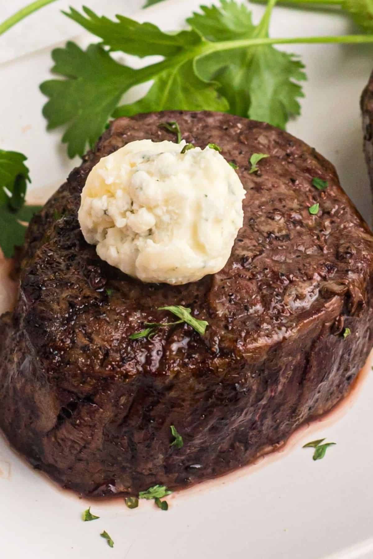 Filet topped with compound butter on a white plate. 