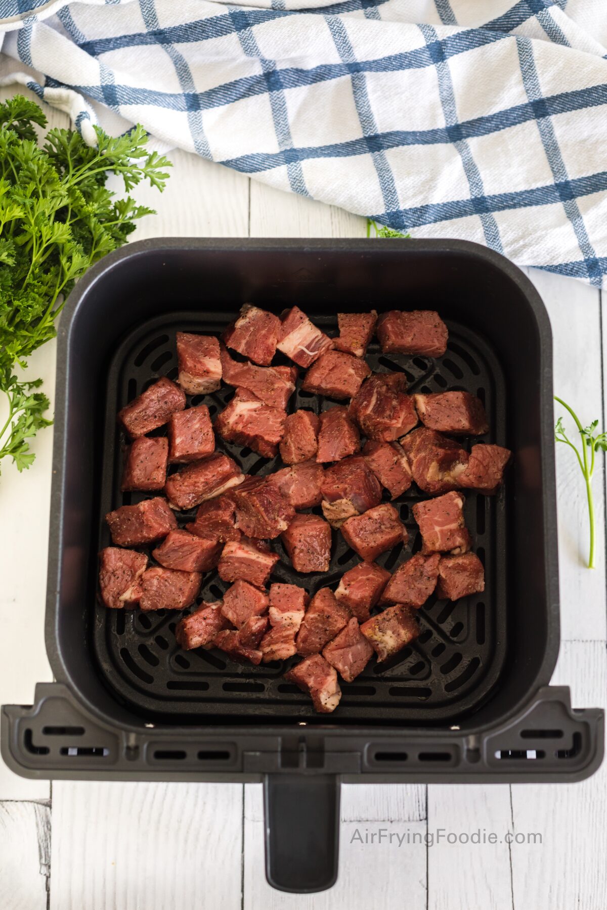 Seasoned steak bites places into a single layer in the air fryer basket. 