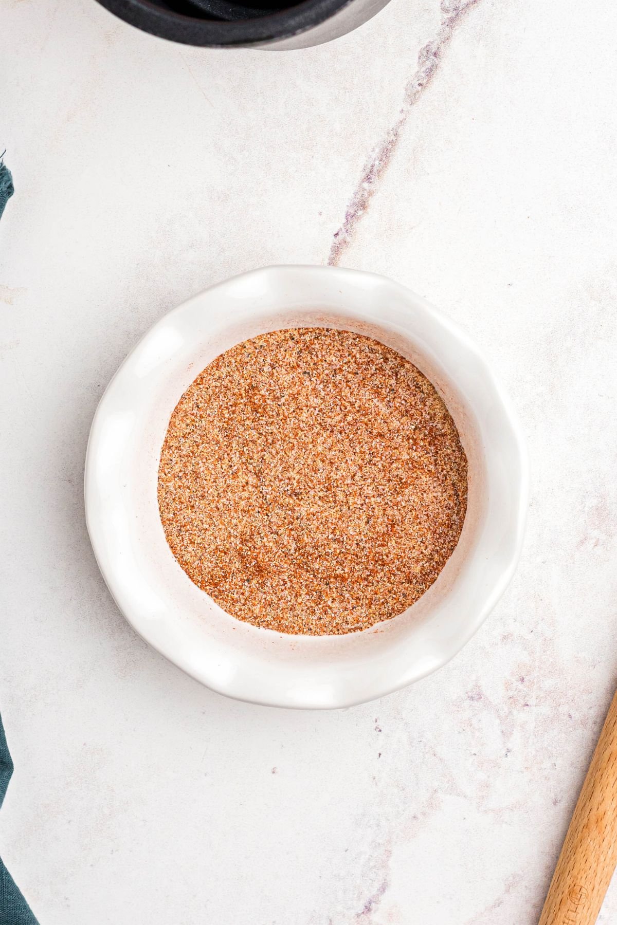 Seasonings mixed together in a small white bowl on a marble counter. 