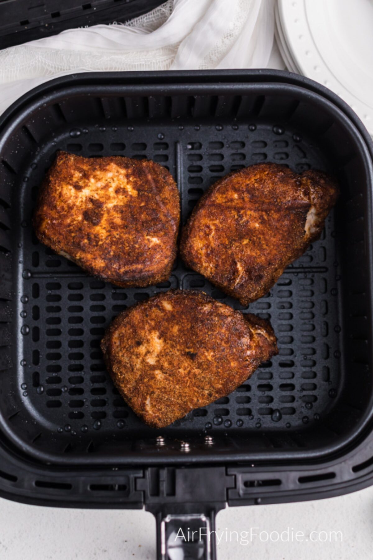 Pork chops in the basket of the air fryer, fully cooked and ready to serve. 