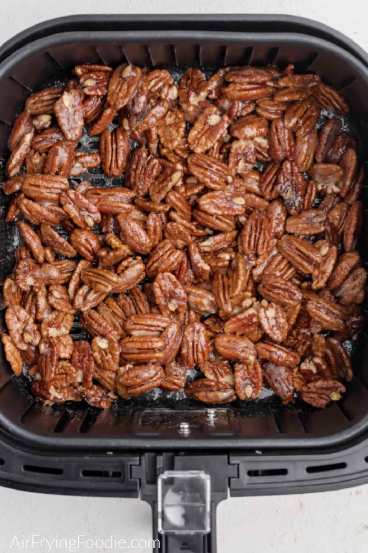 candied pecans in the basket of the air fryer, ready to be cooked. 