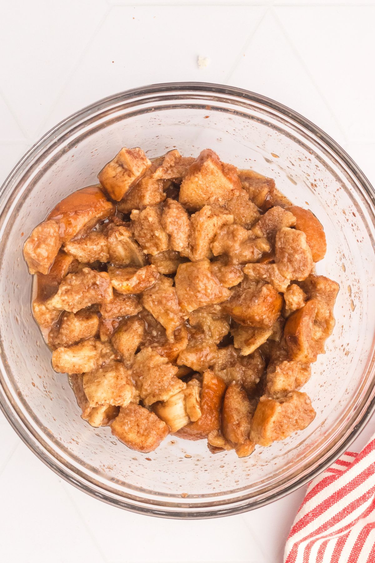 Bites of bread in a large bowl mixed with egg and vanilla to make French toast bites. 