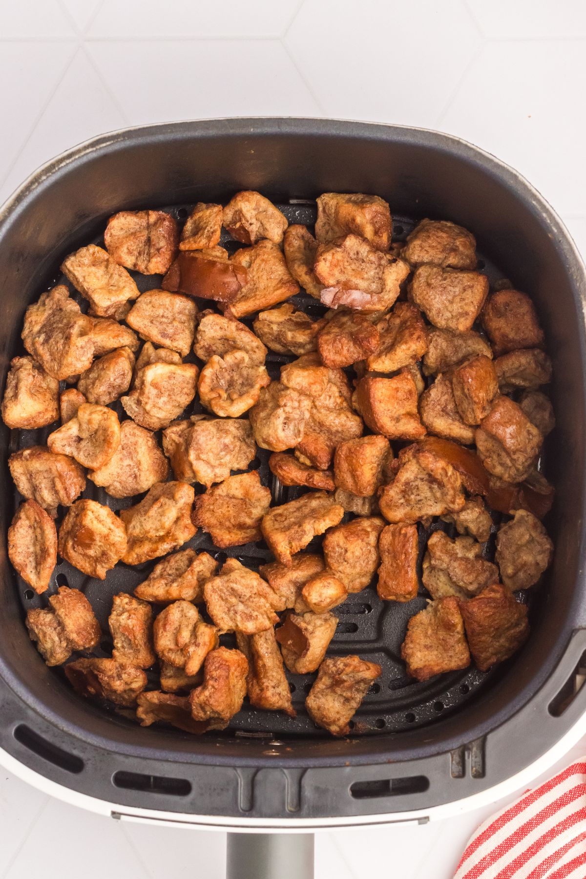 Golden French toast bites in the air fryer basket after cooking. 